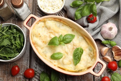 Photo of Tasty vegetarian lasagna and ingredients on wooden table, flat lay