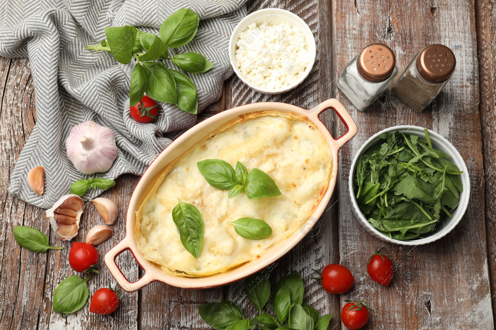 Tasty vegetarian lasagna and ingredients on wooden table, flat lay Photo of Tasty vegetarian lasagna and ingredients on wooden table, flat lay