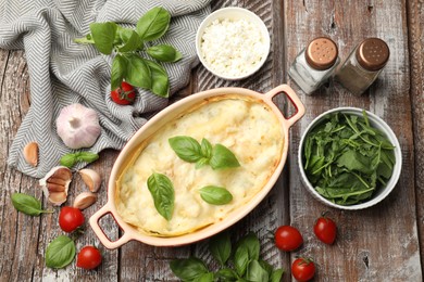 Photo of Tasty vegetarian lasagna and ingredients on wooden table, flat lay