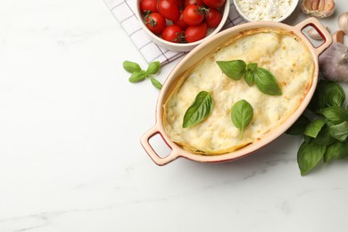 Photo of Tasty vegetarian lasagna and ingredients on white marble table, flat lay. Space for text