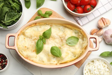 Photo of Tasty vegetarian lasagna and ingredients on white marble table, flat lay
