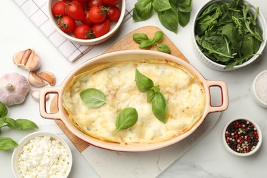 Photo of Tasty vegetarian lasagna and ingredients on white marble table, flat lay