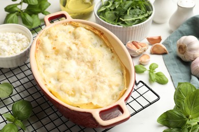 Photo of Tasty vegetarian lasagna and ingredients on white marble table, closeup