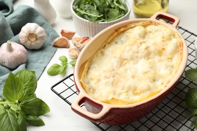 Photo of Tasty vegetarian lasagna and ingredients on white marble table, closeup
