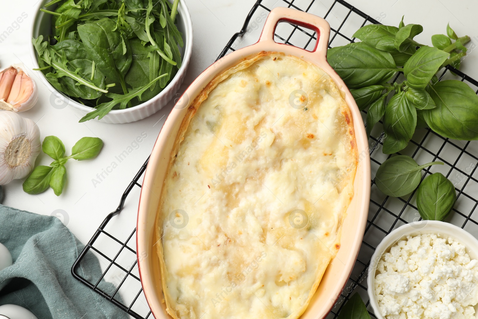 Tasty vegetarian lasagna and ingredients on white table, flat lay Photo of Tasty vegetarian lasagna and ingredients on white table, flat lay