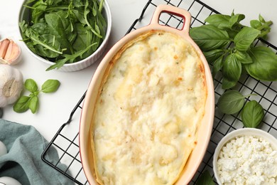 Photo of Tasty vegetarian lasagna and ingredients on white table, flat lay