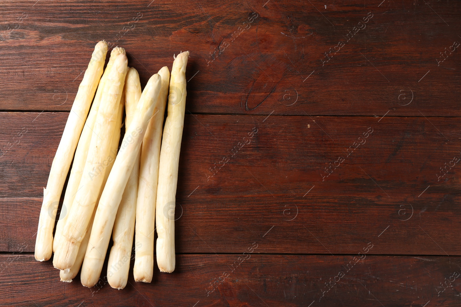 Photo of Many raw asparagus spears on wooden table, top view. Space for text