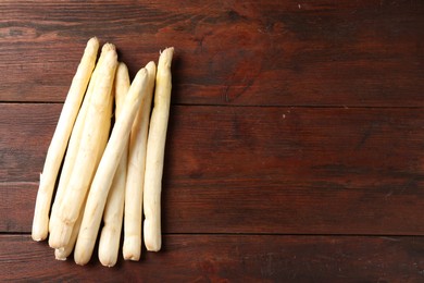 Photo of Many raw asparagus spears on wooden table, top view. Space for text