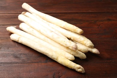 Photo of Many raw asparagus spears on wooden table, closeup
