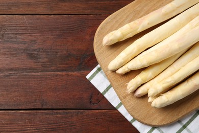 Photo of Raw asparagus spears on wooden table, top view. Space for text