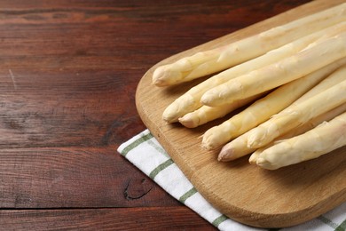 Photo of Raw asparagus spears on wooden table, closeup. Space for text