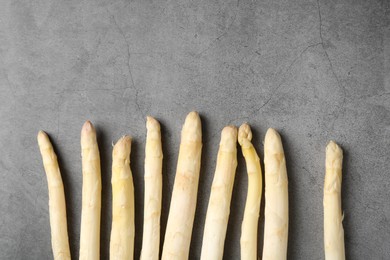 Photo of Many raw asparagus spears on grey table, flat lay. Space for text