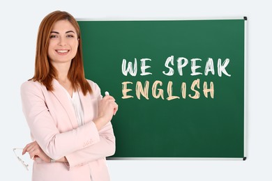 Image of Teacher near green chalkboard with text We Speak English. Language course