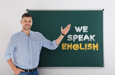 Image of Teacher pointing at green chalkboard with text We Speak English. Language course