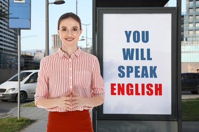 Image of Teacher near advertising board with text You Will Speak English in city. Language course