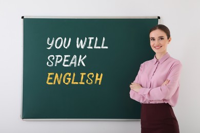 Image of Teacher near green chalkboard with text You Will Speak English. Language course