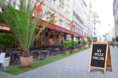 Image of We Speak English text on advertising board in city. Language course