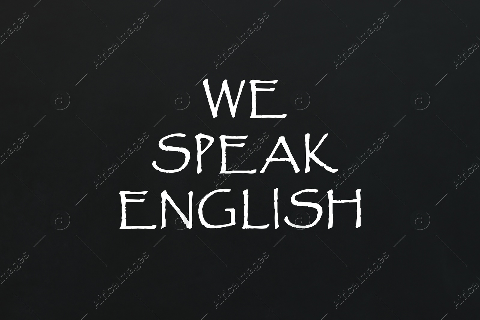 We Speak English inscription on black chalkboard. Language course Image of We Speak English inscription on black chalkboard. Language course