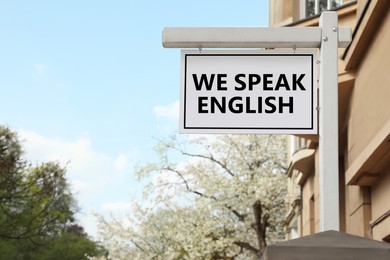 Image of We Speak English text on advertising board in city. Language course