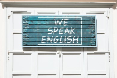 Image of We Speak English text on advertising board outdoors. Language course