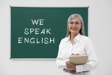 Image of Teacher near green chalkboard with text We Speak English. Language course