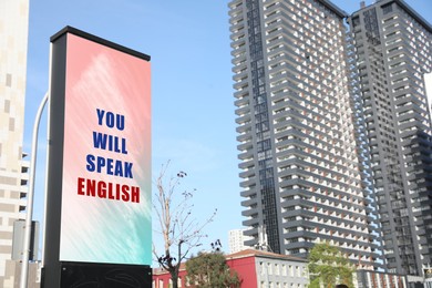 Image of You Will Speak English text on advertising board in city. Language course