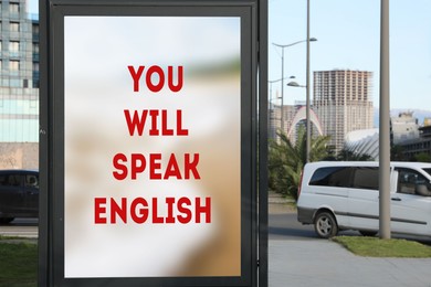 Image of You Will Speak English text on advertising board in city. Language course