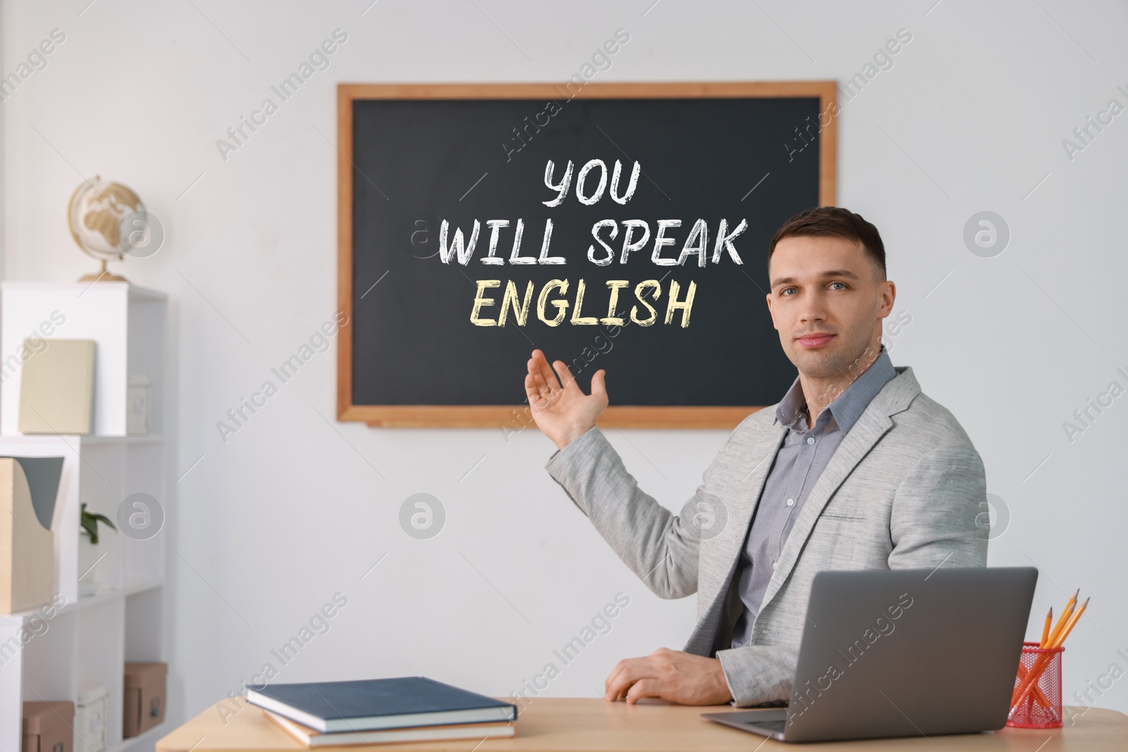 Teacher pointing at text You Will Speak English on black chalkboard in classroom. Language course Image of Teacher pointing at text You Will Speak English on black chalkboard in classroom. Language course