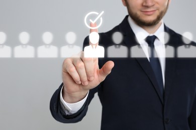 Image of Human resources manager putting check mark over candidate icon on virtual screen against grey background, closeup