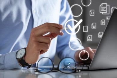 Image of Man putting check mark on virtual screen while working on laptop at table, closeup