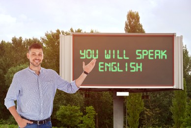 Image of Teacher pointing at text You Will Speak English on digital billboard outdoors. Language course
