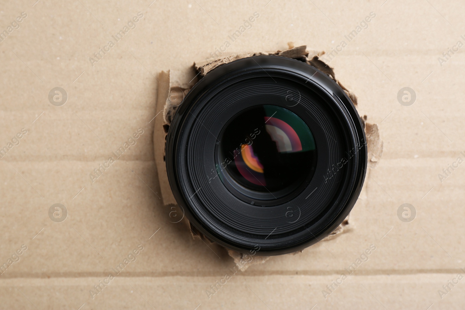 Hidden camera lens through hole in cardboard, closeup Photo of Hidden camera lens through hole in cardboard, closeup