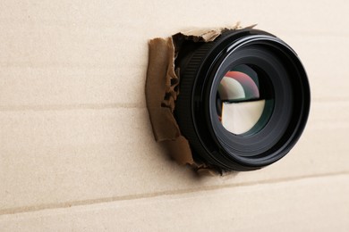 Photo of Hidden camera lens through hole in cardboard, closeup. Space for text