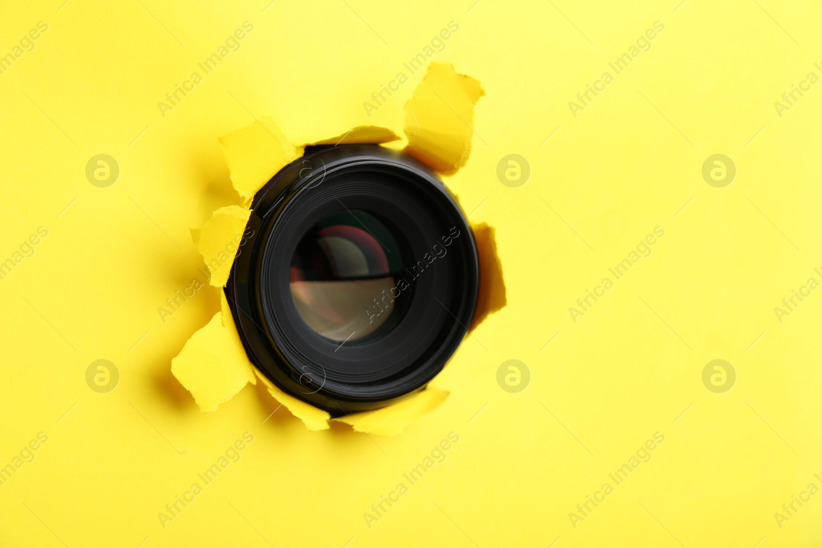 Hidden camera lens through hole in yellow paper Photo of Hidden camera lens through hole in yellow paper