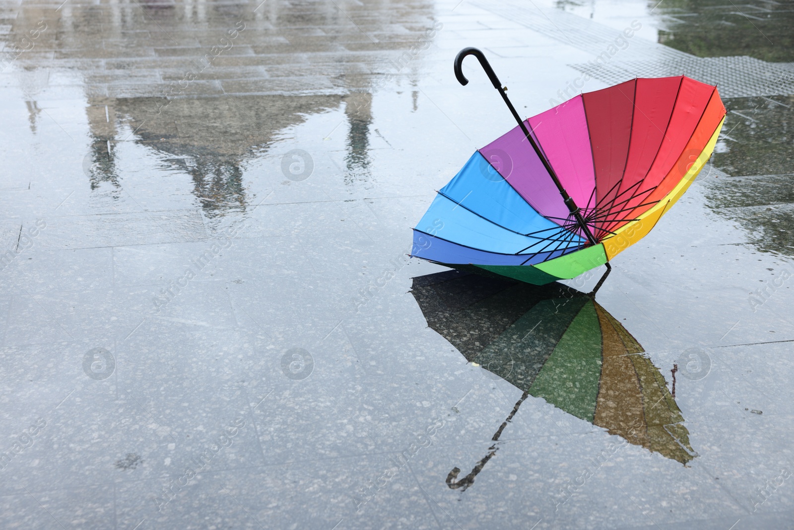 Colorful umbrella on wet asphalt outdoors, space for text Photo of Colorful umbrella on wet asphalt outdoors, space for text