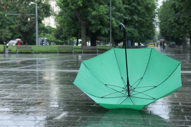 Photo of Green umbrella under heavy rain outdoors, space for text