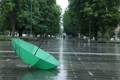 Photo of Green umbrella under heavy rain outdoors, space for text