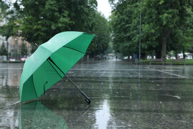 Photo of Green umbrella under heavy rain outdoors, space for text