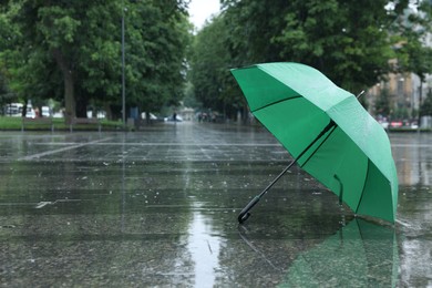 Photo of Green umbrella under heavy rain outdoors, space for text