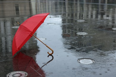 Photo of Red umbrella under heavy rain outdoors, space for text