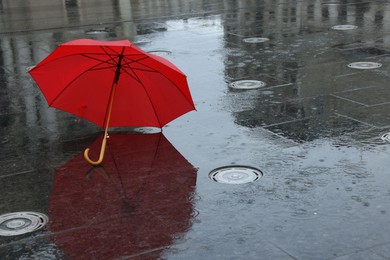 Photo of Red umbrella under heavy rain outdoors, space for text