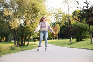 Photo of Beautiful young woman roller skating in park