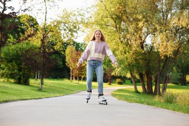 Photo of Beautiful young woman roller skating in park