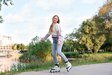 Photo of Beautiful young woman roller skating in park