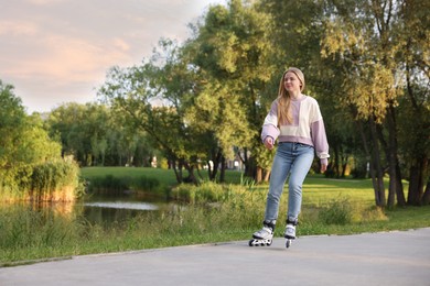 Photo of Beautiful young woman roller skating in park