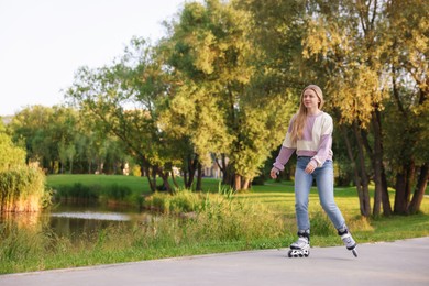 Photo of Beautiful young woman roller skating in park