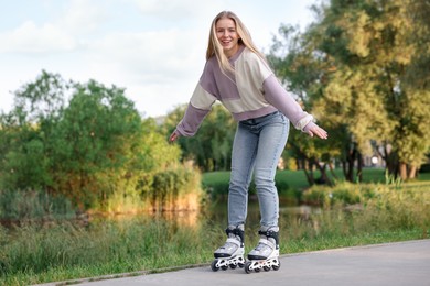 Photo of Happy young woman roller skating in park