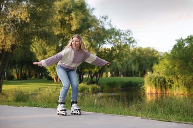 Photo of Happy young woman roller skating in park