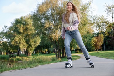 Photo of Happy young woman roller skating in park, low angle view