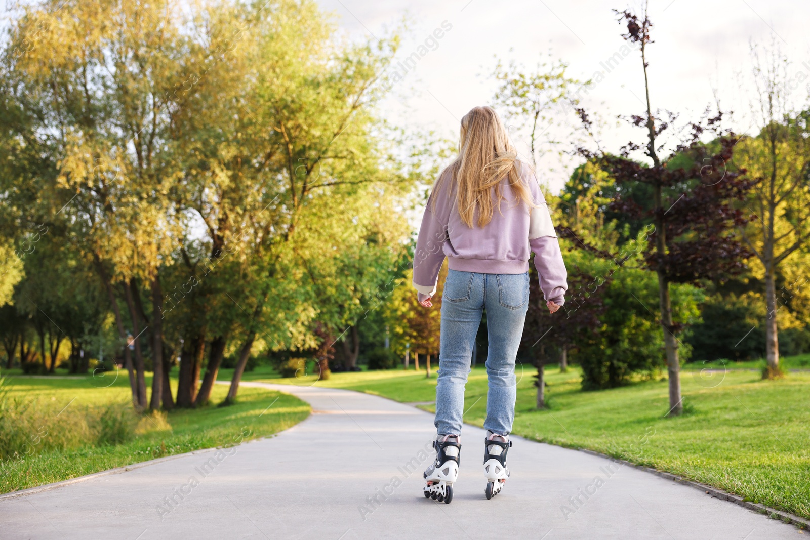 Young woman roller skating in park, back view Photo of Young woman roller skating in park, back view